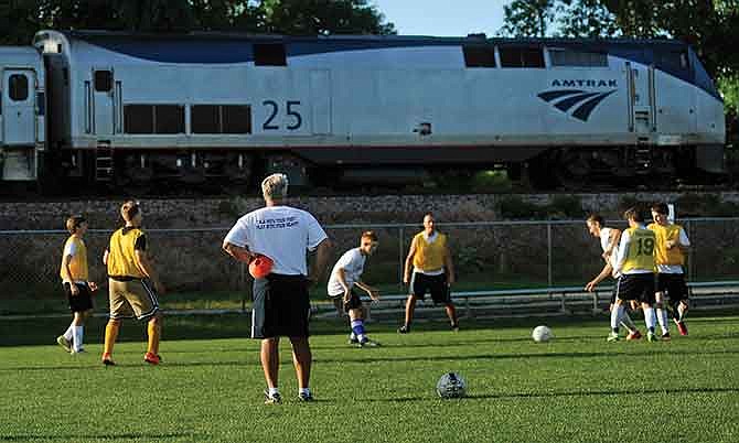 As an Amtrak train passes, a group of soccer campers work on a passing drill under the watchful eye of Helias head boys soccer coach Chuck Register during a late afternoon session in 2013 at the 179 Soccer Park in Jefferson City.