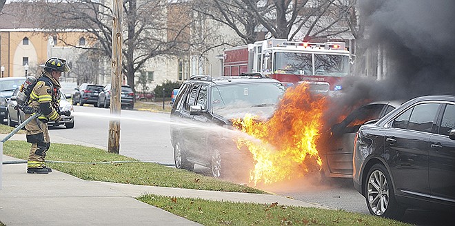 A Jefferson City firefighter tries to extinguish a burning car on Capitol Avenue after it crashed into three parked vehicles.