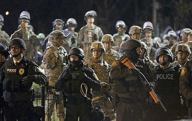 In this Nov. 28, 2014 file photo Police and Missouri National Guardsmen stand guard as protesters gather in Ferguson, Mo. Missouri Gov. Jay Nixon on Wednesday, Dec. 17, 2014 ended the state of emergency for unrest in the St. Louis area related to the grand jury announcement in the Ferguson case, lauding the efforts of police and the Missouri National Guard for preventing any loss of life. 