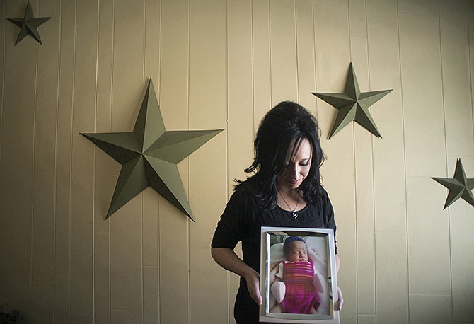 In this November photo, Jennifer Blaz, 34, poses for a photo in her home in Butte, Montana, holding a photograph of her daughter, Mattisyn Blaz. Earlier that day, Matthew Blaz, 33, was sentenced to life in prison without parole for the death of their infant daughter. 