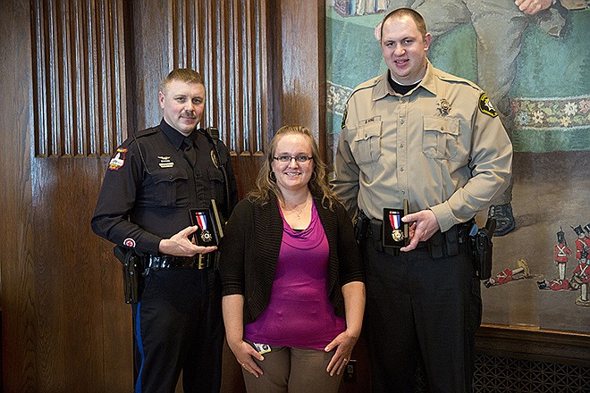 Officers Jason Sederwall, left, and Brad King, right, pose for a 2014 photo with Katherine O'Neal in the Governor's office in the Capitol. Sederwall and King were the recipients of the Missouri's Medal of Valor after saving O'Neal from a burning car on Dec. 10, 2013.