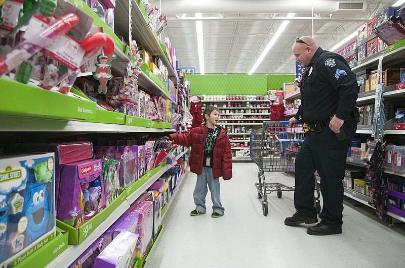 Holts Summit Police Officer Tim Wayant shops with Tristen Mandry, 5, on Saturday at the Fulton Walmart during the annual Shop With a Cop event. The program served 47 children, giving each a stocking donated by Dollar General and $100 gift card to Walmart to spend on themselves and family for Christmas gifts. Personell from the Callaway County Sheriff's Office, New Bloomfield Police and Fire, Fulton Police and Fire, Callaway County EMS, Department of Corrections and Missouri State Highway Patrol participated, helping children pick out gifts. This was also the first year of participation from the United States Army.