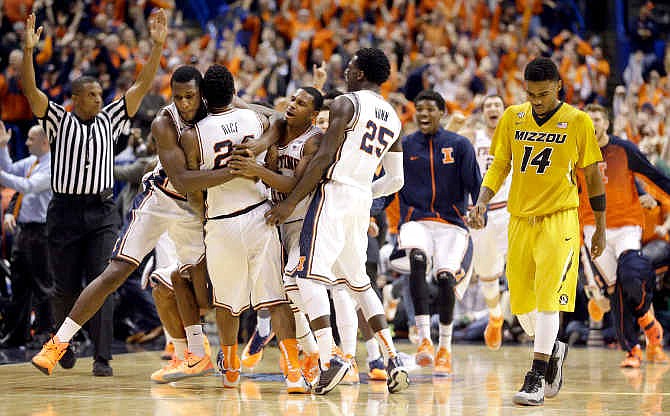 Missouri's Keith Shamburger, right, walks off the court as Illinois' Rayvonte Rice is mobbed by teammates after Rice made a three-point shot at the buzzer to defeat Missouri 62-59 during an NCAA college basketball game, Saturday, Dec. 20, 2014, in St. Louis.