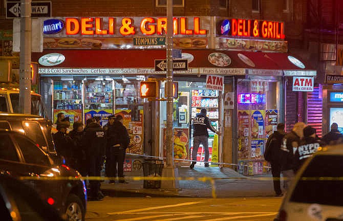 Investigators work in the area where two NYPD officers were shot in the Bedford-Stuyvesant neighborhood of the Brooklyn borough of New York on Saturday, Dec. 20, 2014. Police said an armed man walked up to two officers sitting inside a patrol car and opened fire before running into a nearby subway station and committing suicide. Both police officers were killed. 