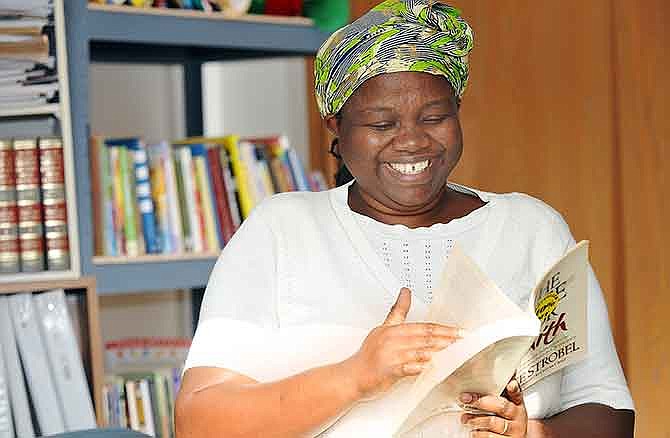 Uwizeyimana Judith has acquired a number of books, as shown behind her, in her quest to learn the English language. She worked, with help from ABLE, to learn English and take and pass her GED in an effort to go on to college for a nursing degree.