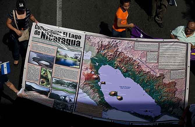 In this Dec. 10, 2014 file photo, protesters carry a banner with a map of Lake Nicaragua during a national march against the construction of the planned inter-oceanic canal in Managua, Nicaragua. Many complain President Daniel Ortega is giving too much away to HKND, the Hong Kong-based company set to develop and operate it. Landowners fear they'll be displaced without fair compensation. Environmentalists accuse the government of ram-rodding past mandated reviews and ignoring the threat that cargo traffic will pose to Lake Nicaragua, the country's main source of fresh water.