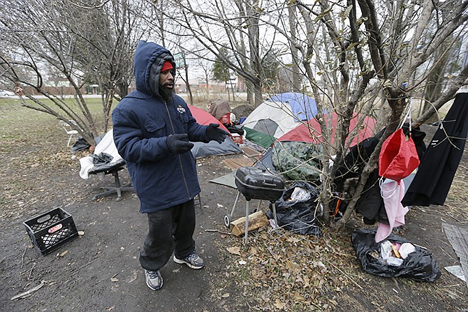 Charles Floyd Jones picks up trash at the tent city on the eastern edge of downtown Detroit. Jones can only hope the city's good fortune trickles down to him and the 10 other residents of a tent city that's sprouted in the shadow of a resurgent downtown where rental occupancy is close to full and retail square-footage fetches top dollar. 