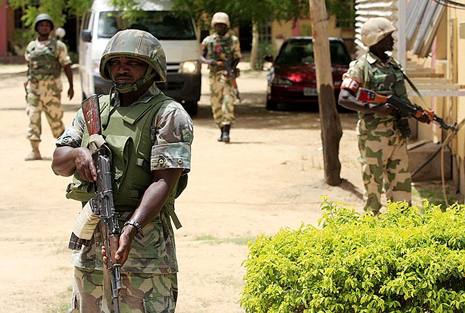 Nigerian soldiers stand guard during 2013 at the offices of the state-run Nigerian Television Authority in Maiduguri, Nigeria. Thousands of members of Nigeria's home-grown Islamic extremist Boko Haram group strike across the border in Cameroon, with coordinated attacks on border towns, a troop convoy and a major barracks. 