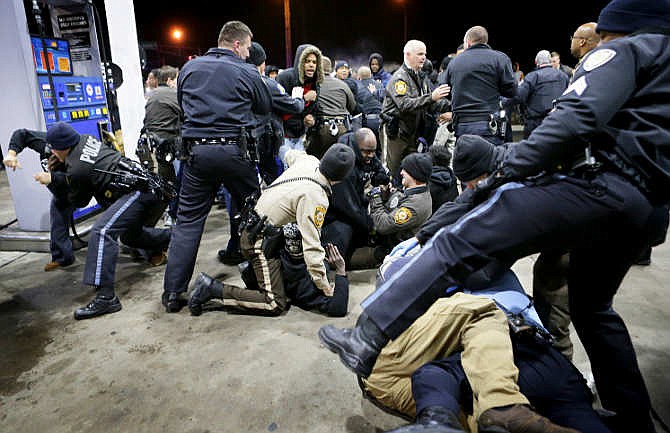 Police try to control a crowd Wednesday, Dec. 24, 2014, on the lot of a gas station following a shooting Tuesday in Berkeley, Mo. St. Louis County police say a man who pulled a gun and pointed it at an officer has been killed.