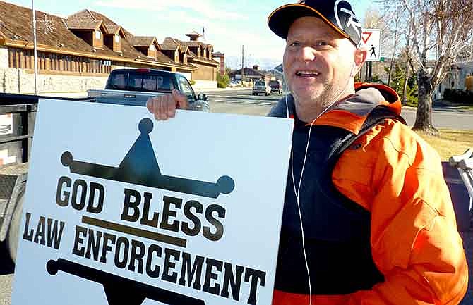 In this Dec. 22, 2014 photo, passing motorists honk as retired Douglas County sheriff's deputy John Munk of Gardnerville, Nev., holds a sign showing his support for law enforcement, in front of the Minden Post Office south of Carson City. "It's disheartening how people are treating law enforcement across the country,'' said Munk, who retired in 2012 after more than 20 years on the force. 