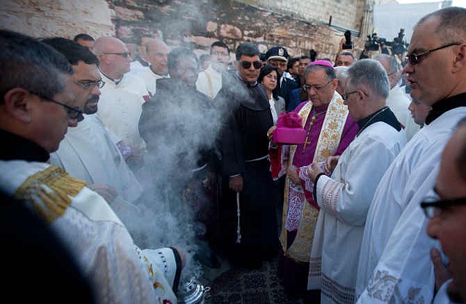 Latin Patriarch of Jerusalem Fouad Twal, center right, arrives at the Church of the Nativity, built atop the site where Christians believe Jesus was born, on Christmas Eve in the West Bank town of Bethlehem on Wednesday, Dec. 24, 2014. Christian pilgrims from around the world have begun to gather in the biblical town of Bethlehem for Christmas Eve celebrations in the traditional birthplace of Jesus.