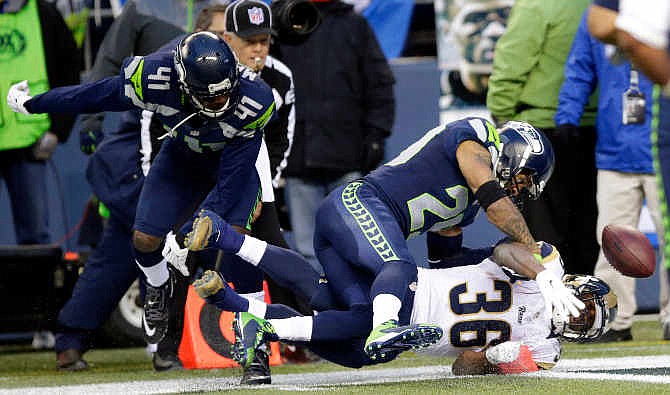 St. Louis Rams running back Benjamin Cunningham (36) fumbles in the end zone and the ball goes out of bounds for a touchback under pressure from Seattle Seahawks cornerback Byron Maxwell (41) and Earl Thomas, center, in the second half of an NFL football game, Sunday, Dec. 28, 2014, in Seattle.