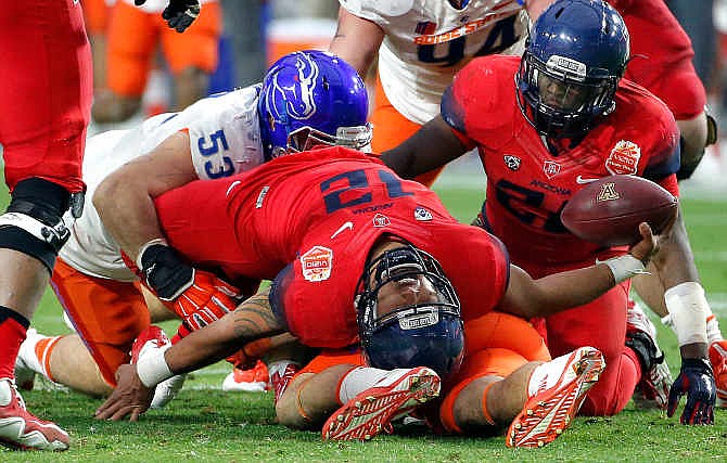 Arizona quarterback Anu Solomon (12) falls backwards after being hit by Boise State defensive end Beau Martin (53) during the first half of the Fiesta Bowl NCAA college football game, Wednesday, Dec. 31, 2014, in Glendale, Ariz. 