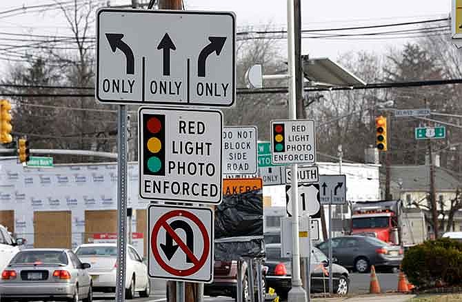 In a Tuesday, Dec. 16, 2014 file photo, traffic passes a red light photo enforcement sign below a red light camera at the intersection of Route 1 and Franklin Corner Road, in Lawrence Township, N.J. New Jersey legislators recently discontinued the state's red light camera pilot program after five years. The number of red-light cameras nationwide is falling because of opposition from lawmakers and average Joes _ but the use of cameras to catch speeders is slowly rising, potentially signaling a new battleground. 