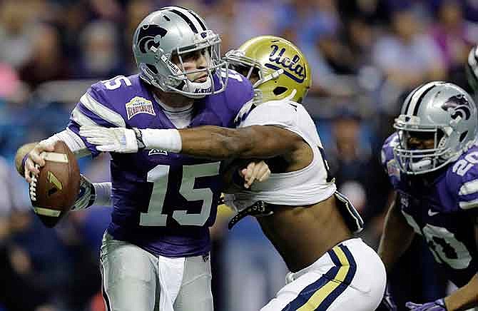 Kansas State's Jake Waters (15) is hit by UCLA's Deon Hollins as he tries to pass during the first half of the Alamo Bowl NCAA college football game, Friday, Jan. 2, 2015, in San Antonio.