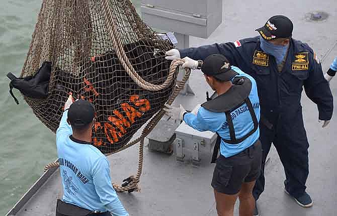 Bags containing dead bodies of the passengers of AirAsia Flight 8501 are lifted onto Indonesian navy vessel KRI Banda Aceh at sea off the coast of Pangkalan Bun, Indonesia, Saturday, Jan. 3, 2015. Indonesian officials were hopeful Saturday they were honing in on the wreckage of the flight after sonar equipment detected two large objects on the ocean floor, a full week after the plane went down in stormy weather.
