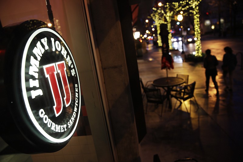 Pedestrians pass by a Jimmy John's sandwich shop, Friday, Jan. 2, 2015, in Atlanta. A lawsuit targeting the fast-food sandwich chain has put scrutiny on agreements banning low- and middle-wage workers from competing against their former employers.