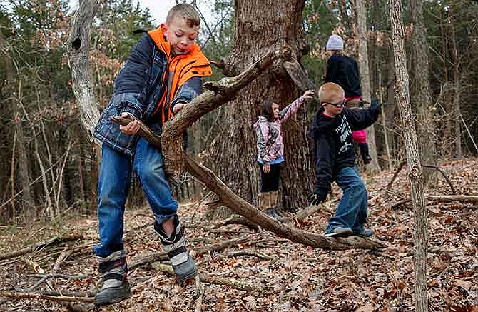 Jesse Jorgensen, left, and Cole Peters, right -- participants in the annual Winter Day Hike at Runge Nature Center in Jefferson City -- climb on trees Friday afternoon after practicing to build an emergency shelter.