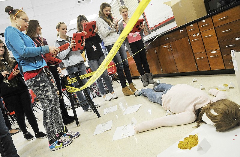Using iPads to take photographs and notes, students in the Principles of Biomedical Science class at Simonsen Freshman School document the crime scene in the corner of the room. This falls under the Health Services Academy and one course of Project Lead The Way. Students were told this is likely to be one of the most difficult classes they have taken thus far in their educational history but will likely be the one in which they will learn the most.
