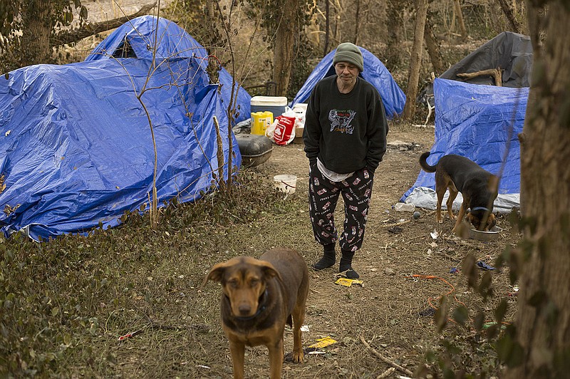 Tim Rigby stands in a tent community set up down the hill behind Dulle-Hamilton Towers on Tuesday with his two dogs Marley, left, and Bear. According to Rigby, he has everything he needs and will continue to live comfortably in his tent despite the cold weather.
