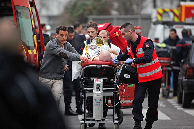 An injured person is transported to an ambulance after a shooting, at the French satirical newspaper Charlie Hebdo's office, in Paris, Wednesday. Masked gunmen stormed the offices of a French satirical newspaper Wednesday, killing at least 11 people before escaping, police and a witness said. The weekly has previously drawn condemnation from Muslims.
