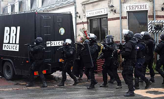 French riot officers patrol in Longpont, north of Paris, France, Thursday, Jan. 8, 2015. Scattered gunfire and explosions shook France on Thursday as its frightened yet defiant citizens held a day of mourning for 12 people slain at a Paris newspaper. French police hunted down the two heavily armed brothers suspected in the massacre to make sure they don't strike again. 