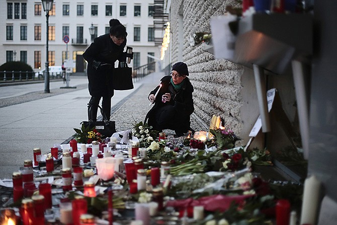 Women light candles to commemorate the victims killed in an attack at the Paris offices of the weekly newspaper Charlie Hebdo, in front of the French Embassy in Berlin, Thursday. Wednesday was France's deadliest postwar terrorist attack. 