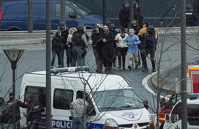 Security officers escort released hostages after they stormed a kosher market to end a hostage situation, Paris, Friday, Jan. 9, 2015. Explosions and gunshots were heard as police forces stormed a kosher grocery in Paris where a gunman was holding people hostage. Two sets of attackers seized hostages and locked down hundreds of French security forces around the capital on Friday, sending the city into fear and turmoil for a third day in a series of linked attacks that began with the deadly newspaper terror attack that left 12 people dead. 