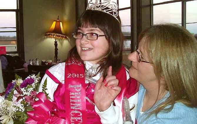 In this Jan. 7, 2015 photo, Molly McKinley sits with her mom Dawn Bricker during a surprise party for her in Hannibal, Mo. The 11-year-old, who has a life-threatening neurological disorder, had asked Make-A-Wish Missouri for a trip to Disney World, but when her illness made that impossible the organization sought to give her a Disney-like party with fireworks in her hometown. Despite bitter temperatures, people in her northeast Missouri community found a way to grant the wish and crown her "Princess Molly." (AP Photo/The Courier-Post, Bev Darr) 