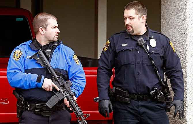 Police officers talk ouside while emergency medical technicians aid one of the shooting victims in Moscow, Idaho, on Saturday, Jan. 10, 2015. Police say a gunman killed three people and critically wounded another during a spree at three locations in Moscow, Idaho. (AP Photo/Moscow-Pullman Daily News, Geoff Crimmins)