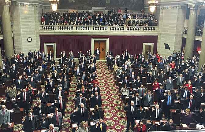 Members of the Missouri House of Representatives stand and are sworn in Wednesday during opening day ceremonies in the state Capitol.