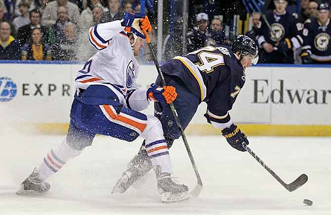 St. Louis Blues' T.J. Oshie (74) spins away from Edmonton Oilers' Nikita Nikitin (86) as he reaches for the loose puck in the second period of a NHL hockey game, Tuesday, Jan. 13, 2015 in St. Louis.