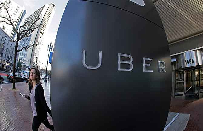 In this Tuesday, Dec. 16, 2014 photo, a woman leaves the headquarters of Uber in San Francisco. Venture capitalists poured a whopping $48.3 billion into U.S. startup companies last year, investing at levels that haven't been seen since before the dot-com bubble burst in 2001, according to a new report issued Friday, Jan. 16, 2015. The two biggest deals in 2014 were separate rounds of investment in Uber Technologies, the high-flying and controversial ride-hailing service, now valued at $41 billion.