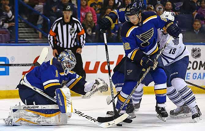 St. Louis Blues goalie Brian Elliott attempts to cover the puck as teammate Kevin Shattenkirk (22) and Toronto Maple Leafs' Richard Panik (18), of the Czech Republic, works in front of the net during the first period of an NHL hockey game Saturday, Jan. 17, 2015, in St. Louis.