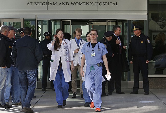 Medical personnel walk past law enforcement officials, right, as they depart the Shapiro building at Brigham and Women's Hospital, Tuesday in Boston. A person was critically shot at the hospital Tuesday and a suspect was in custody, Boston police said.
