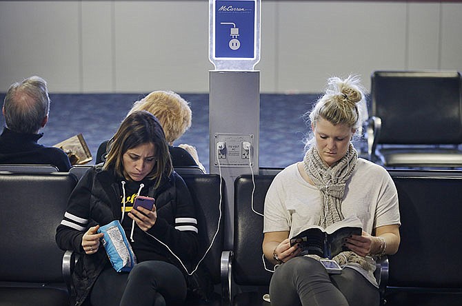 In this Dec. 29, 2014, photo, travelers use a charging station at McCarran International Airport in Las Vegas. While the common lithium-ion battery that's used to power laptops, cellphones and tablet computers has improved in recent years, the demand that us gadget addicts are placing on these batteries has soared.