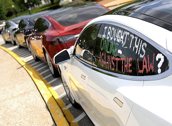 A message is left for display on the window of a Tesla Model S as several of the electric cars sit in front of the Missouri Capitol's south entrance. Auto dealers are suing the state after it gave a dealer license to Tesla.