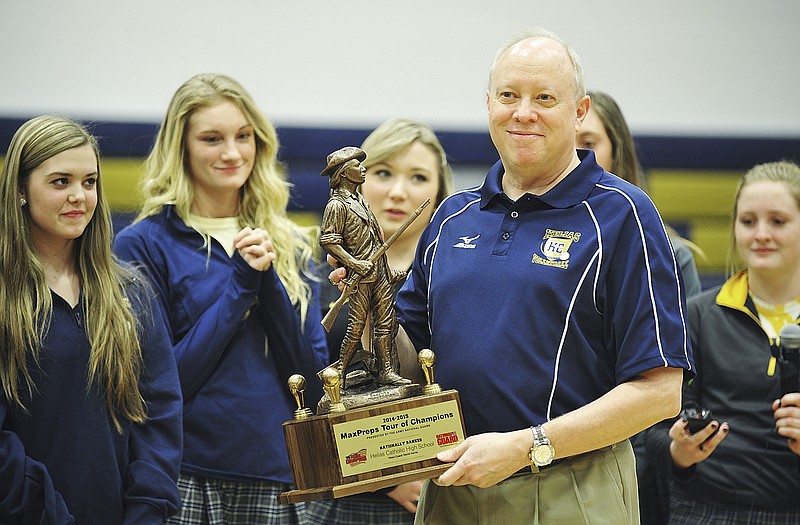 Flanked by team members, Helias volleyball coach David Harris stands with the Army National Guard Minuteman award  presented by MaxPreps during a school assembly Friday at Rackers Fieldhouse. Helias, which went undefeated to win the Class 3 state title this season, is one of 10 teams in the nation to receive the award.