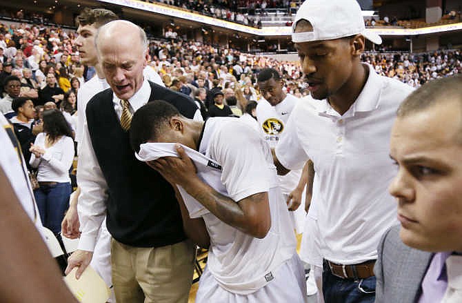 Missouri guard Wes Clark is escorted off the court by Missouri special assistant to the Athletic Director Gary Link (left) and former Missouri star Kim English, right, after Clark missed two free throw attempts to tie the game in the final seconds of an NCAA college basketball game against Arkansas, Saturday, Jan. 24, 2015, in Columbia, Mo. Arkansas won 61-60. 