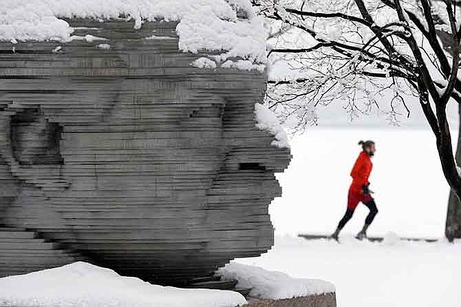 A jogger passes a statue of Arthur Fiedler on the Esplanade in Boston, Saturday, Jan. 24, 2015. A winter storm warning covering Boston and Hartford, Connecticut was in effect through 7 p.m. as the National Weather Service said to expect 4 to 8 inches of wet snow to fall by the time the storm moves out.