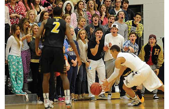 The Helias student section, many wearing pajamas for the game, react as Fulton's Devin Gibson (not pictured) slips in front of them and loses the ball to Isiah Sykes of Helias in the first half of Friday night's game at Rackers Fieldhouse in Jefferson City.