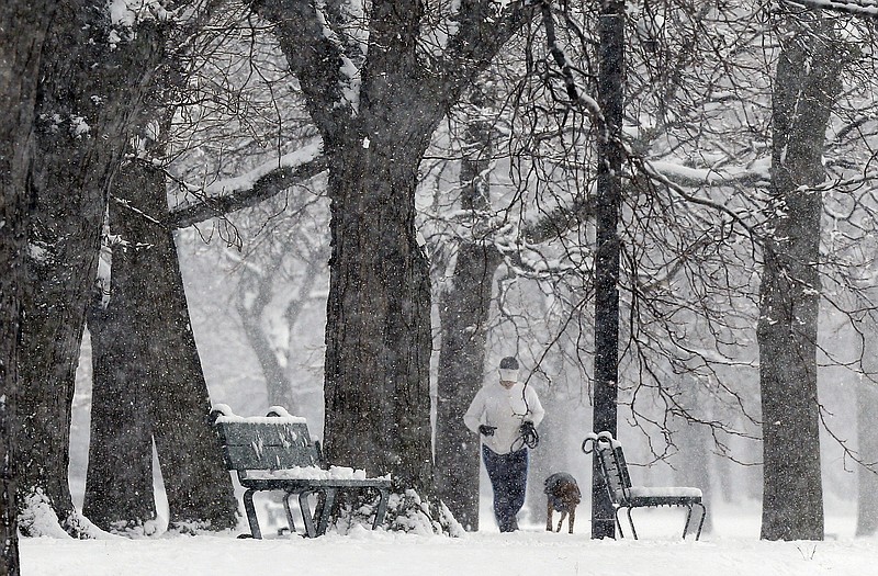 A woman jogs with a dog on the Esplanade in Boston, Saturday. A winter storm warning covering Boston and Hartford, Connecticut was in effect through 7 p.m. as the National Weather Service said to expect 4 to 8 inches of wet snow to fall by the time the storm moves out.