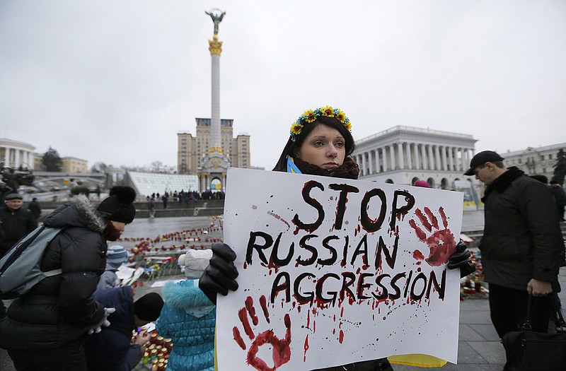 A woman holds a placard during a rally on Independence Square in Kiev, Ukraine, Sunday, in solidarity with the victims of a rocket attack on the coastal city of Mariupol. Indiscriminate rocket fire slammed into a market, schools, homes and shops Saturday in Ukraine's southeastern city of Mariupol, killing at least 30 people.