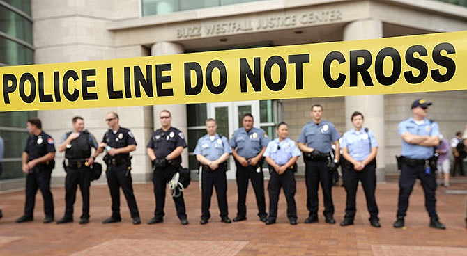 In this August 2014 photo, police guard the entrance to the Buzz Westfall Justice Center in Clayton where a grand jury later decided not to indict the police officer who shot and killed teenager Michael Brown. Grand juries have long held some of the criminal justice system's best-kept secrets. But their private process has come under extraordinary public scrutiny after recent decisions not to indict police in the deaths of unarmed men.
