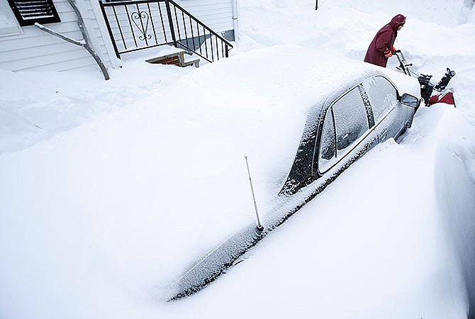 Phil Curran, 71, uses a snowblower to dig out a car that was buried in a snowdrift after a winter storm Wednesday in Portland, Maine. Tuesday's blizzard dumped about two feet of snow in Portland. 
