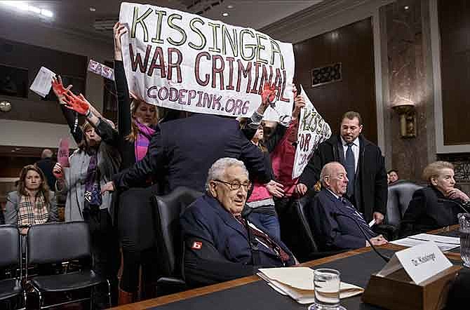 Protesters interrupt the start of a Senate Armed Services hearing, on Capitol Hill in Washington, Thursday, Jan. 29, 2015, as they shout at former Secretary of State Henry A. Kissinger, center, joined by fellow former State Department heads George P. Shultz and Madeleine K. Albright. The upheaval came as members of an anti-war group Code Pink called the 91-year-old Kissinger a war criminal.