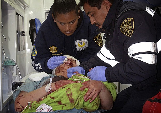 A paramedic holds the hands of a newborn as his colleague attends to the baby's mother, who was evacuated from the maternity and children's hospital in Cuajimalpa, on the outskirts of Mexico City, Thursday.