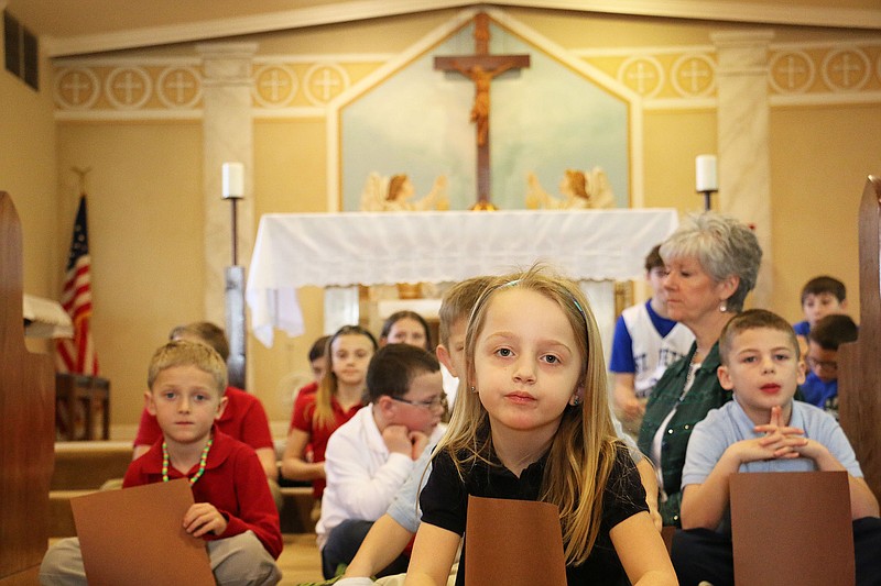 St. Peter Catholic School student Emma and her classmates sit in St. Peter Church, forming a cross. The school formed a living rosary Wednesday morning after mass in honor of National Catholic Schools Week. The school formed a giant circle in the church, with a few students sitting to form a cross.