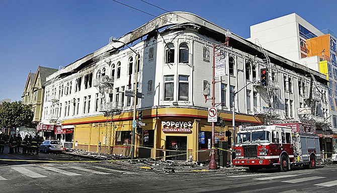 Firemen investigate the scene of a fatal fire Thursday in San Francisco. Officials are investigating whether fire alarms and fire escapes were working properly after a massive blaze ripped through a building in the Mission District, killing a man and injuring five other people.  