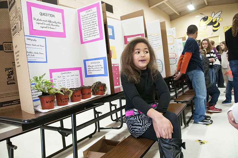 Amaya Travis, a fourth grade student at Bush Elementary, explains her science project Friday during the school's science fair. Students in thrid, fourth and fifth grade showcased their experiments inside the gymnasium, allowing for their younger peers and family members to learn about what the young scientists discovered. Travis tested a plant's reaction when given acids and bases, using water, lemon juice, vinegar, Windex and bleach.